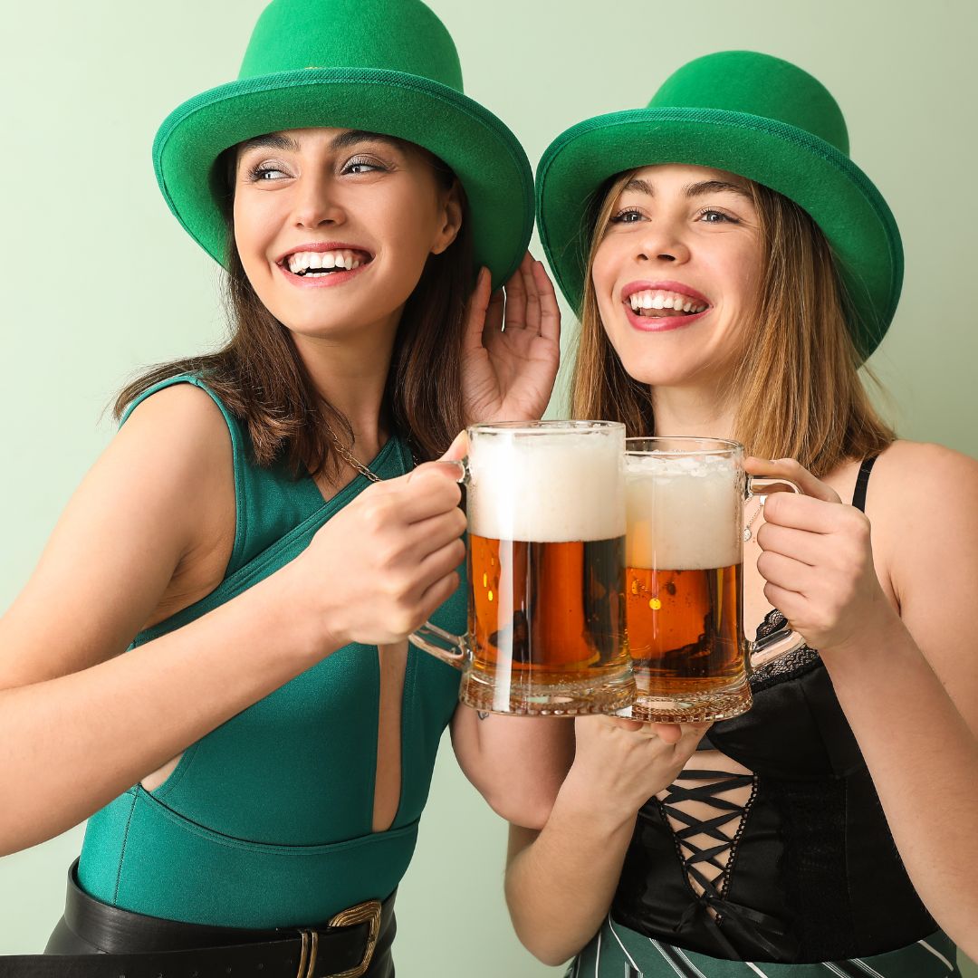 two women wearing Irish costumes and drinking beer